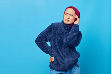 Portrait of young Asian woman looking dizzy and having headache on blue background