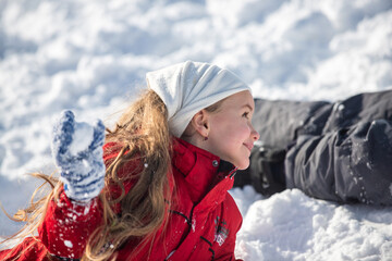 Funny excited child girl face in snow on winter outdoor. Children in winter outdoor in frost snowy day. Amazed kid resting together in park with winter background. Expressive kids emotions.