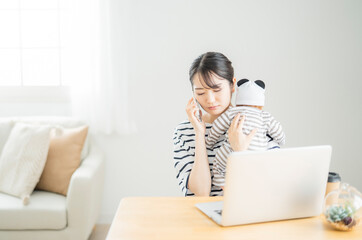 赤ちゃんの世話をしながら電話する女性（困る）
