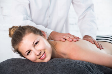 Fototapeta na wymiar Portrait of young american woman enjoying relaxing massage by professional masseur