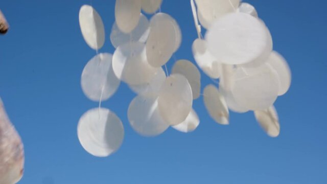 Closeup of Hanging seashells mobile blowing in the wind.