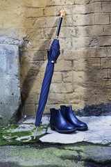 Men's shoes with an umbrella and a walking stick are on the street