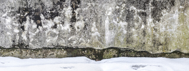 weathered and damaged concrete wall near foundation. winter time. panoramic view.