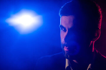 Close up photo of male face and blue light on the background.
