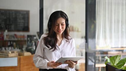 Smiling asian businesswoman siting in coffee shop and using digital tablet.