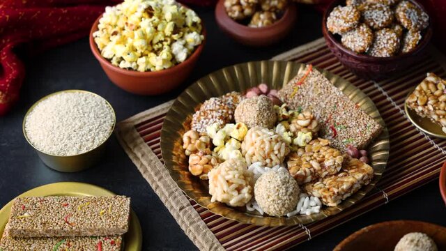 Til chikki Murmura ladoo peanut chikki laddu Revdi popcorn Indian festival snack sweet Lohri Makar Sankranti Pongal Diwali 4K video footage winter food served in golden plate Tamil Nadu Punjab India
