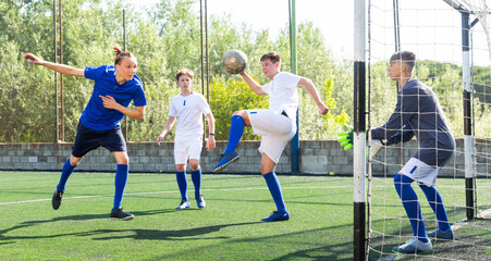 Youthful football players challenging for ball in goalmouth zone
