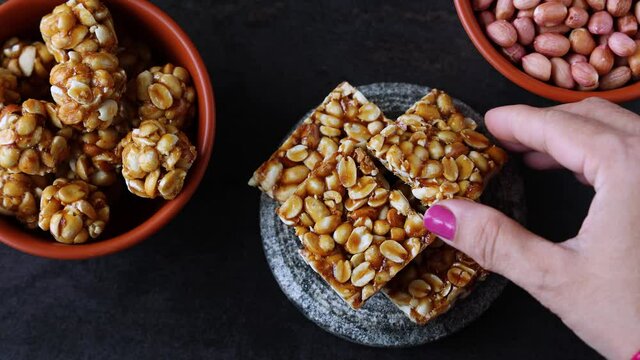 Peanut chikki peanut candy groundnut sweet Kadalai mittai woman hand serving winter food Indian festival food snack Lohri Makar Sankranti Pongal Diwali 4K video footage Tamil Nadu Punjab North India