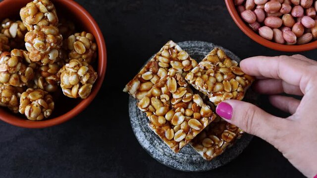 Peanut chikki peanut candy groundnut sweet Kadalai mittai woman hand serving winter food Indian festival food snack Lohri Makar Sankranti Pongal Diwali 4K video footage Tamil Nadu Punjab North India