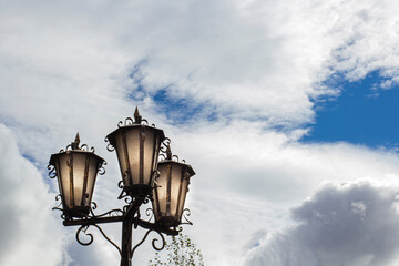 Beautiful street lights or lamps on the background of the evening sky with clouds