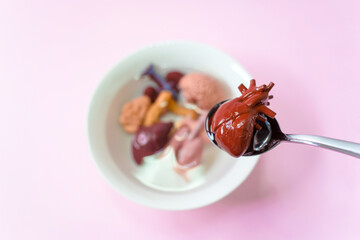 Human heart in the spoon and human internal organs with soup in white bowl, Every food you eat has an effect on your body.