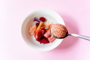 Human brain in the spoon and human internal organs with soup in white bowl, Every food you eat has an effect on your body.