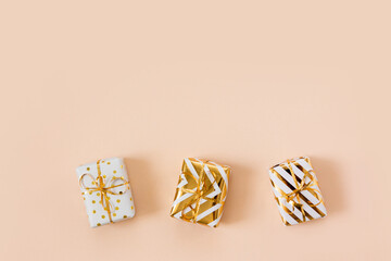 White gift boxes with golden bow isolated on beige pastel background. Christmas and new year shopping and sale. Copy space, frame. Banner. Holiday and celebration concept
