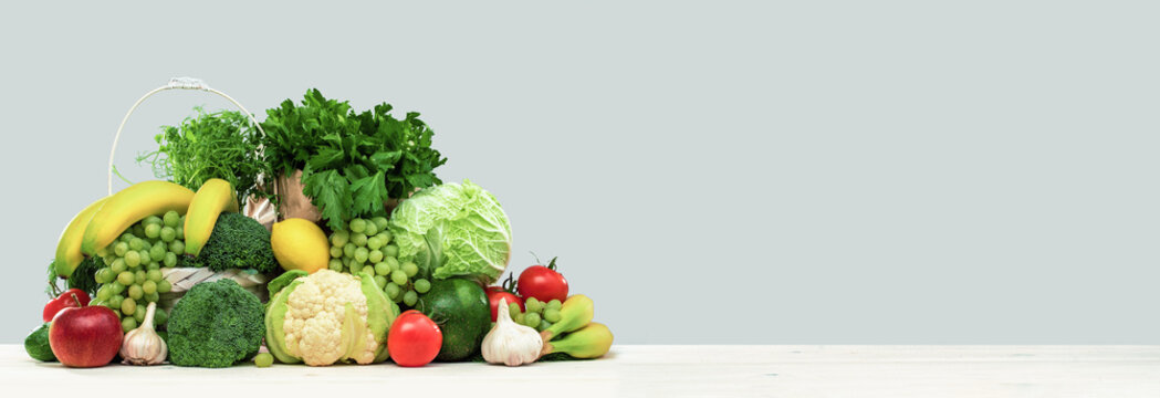 Fresh green vegetables in a basket on a wooden table. Banner with copy space. Green vegetarian diet or cuisine. Broccoli cabbage and celery. Grocery delivery or shopping online. Green diet