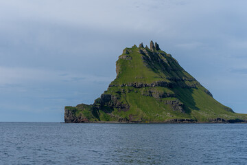 View of the impressive Rocky Drangarnir sea stack and the fishing farms in the Faroe Islands seen from the ferry to Mykines 