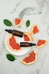 top view of a white plate with two bottles-dropper with grapefruit oil and fruit slices. moisturizing, aromatherapy, anti-stres effect.