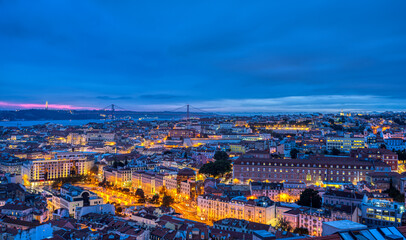 Lisbon in Portugal at night with the Sanctuary of Christ the King and the 25 de Abril Bridge in the back