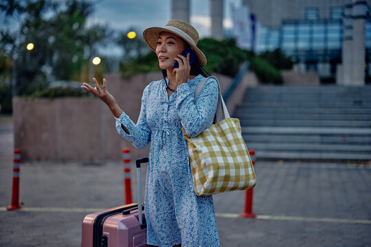 Asian female traveler talking on phone outdoors