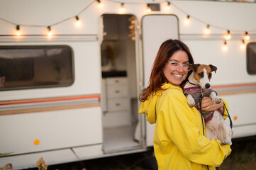 Red-haired Caucasian woman hugs a dog and lives in a motor home. Travel by trailer.