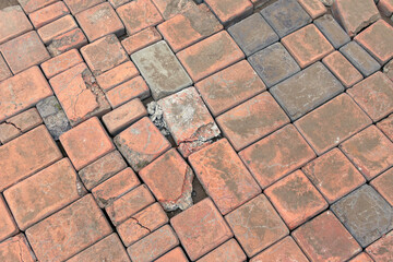 Old broken paving stones. The road is paved with red broken bricks. The texture of the old broken tiles