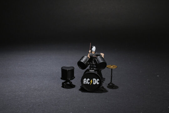 a mini figure of caucasian man practice playing on drums before concer