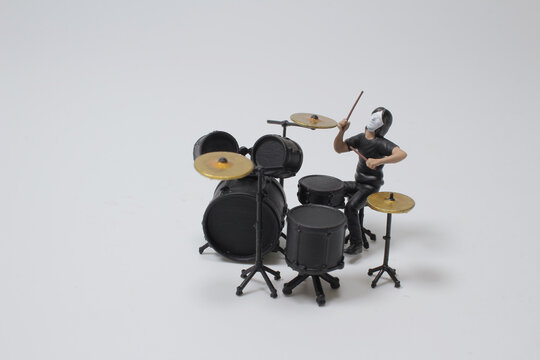 a mini figure of caucasian man practice playing on drums before concer