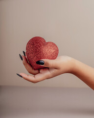 Halloween theme: hand with black nails hold torn bleeding human heart