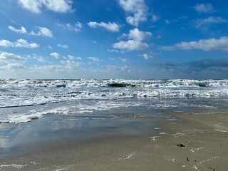 Waves on the sea on the shore against the blue sky during the day. Foam waves.