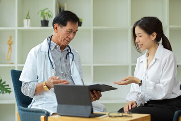 an Asian female patient consults with a middle-aged specialist doctor