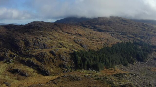 Carlingford Lough, Louth, Ireland, October 2021. Drone tracks west over rugged mountains revealing a view of the lough with Mourne mountains in the distance.