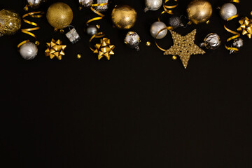 Christmas background with fir branches, gold decorations and pine cones on a black table. Flat lay. top view with copy space