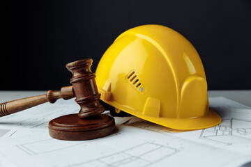 Wooden gavel and yellow helmet with construction plans