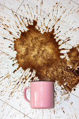 Pink cup fell on white parquet floor left a big stain. Spilled coffee splashes.