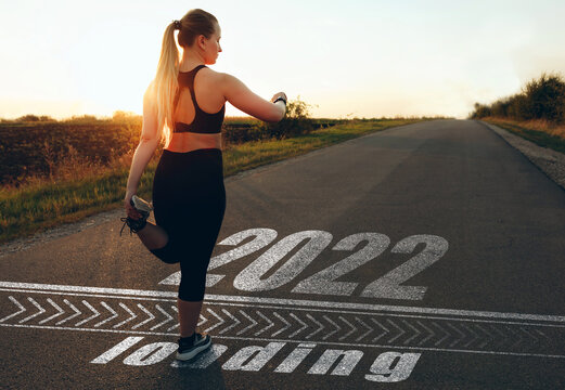 Woman  who is at the starting line to pass in 2022 year and the Loading bar drawn on asphalt. 
Concept of successful achievements in the new year 2022.New Year 2022. New Goals, Plans and Visions