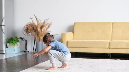 boy doing squats. Positive carefree little boy exercising training at home indoors having fun. - Powered by Adobe