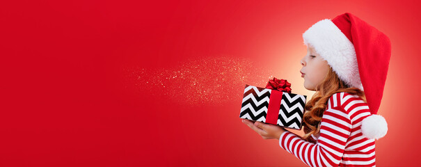 Christmas banner child in a santa hat holding a gift on a red background with place for text	
