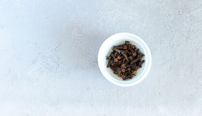 Dry cloves spices in white plate isolated on gray background. High quality photo