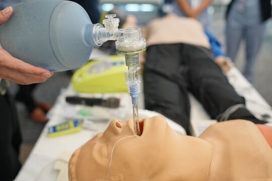 A healthcare professional demonstrates intubation on a manikin using a bag valve mask, highlighting emergency airway management and medical training.