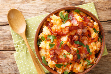 Mashed potatoes and carrots with bacon close-up in a bowl on the table. horizontal top view from above