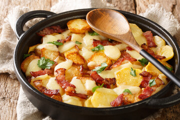 Fresh Aubrac truffade potatoes with cheese and bacon close up in the pan on the table. Horizontal