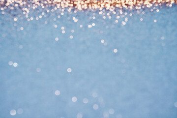 Blue festive background. Abstract scattering of gold sparkles. Christmas Winter backdrop, selective focus