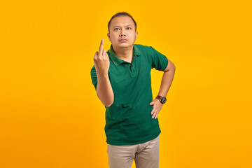 Portrait of angry handsome man showing middle finger to camera on yellow background