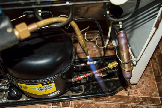 Oxygen gas welding during the repair of a refrigerator unit. Oxygen welding. Refrigeration unit motor. Service maintenance. Household appliances repair workshop. Industrial equipment.