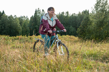 Cheerful grandmother rides a bicycle in nature.