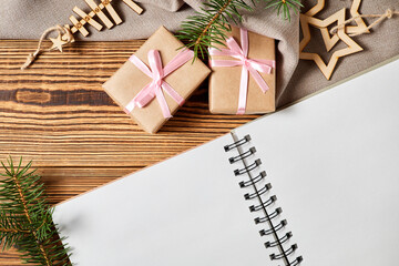 Blank notepad on background of gift boxes, wooden stars and new year tree on wooden background