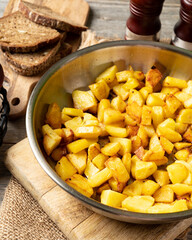 Fried potatoes in a frying pan on a gray wooden table closeup	
