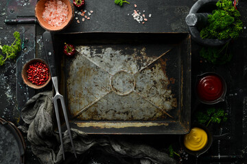 Black stone cooking background. Metal tray, Spices and vegetables. Top view. Free space for your text.