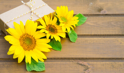 Craft gift box and bright sunflower flowers on wooden background