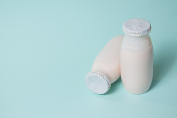 Bottles with probiotics and prebiotics dairy drink on light blue background.