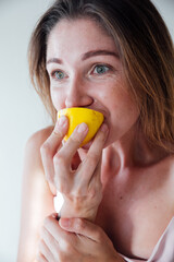 beautiful woman with blond hair eat a yellow sour lemon